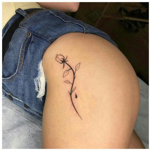Татуировка на бедре у девушки в виде нежного цветка