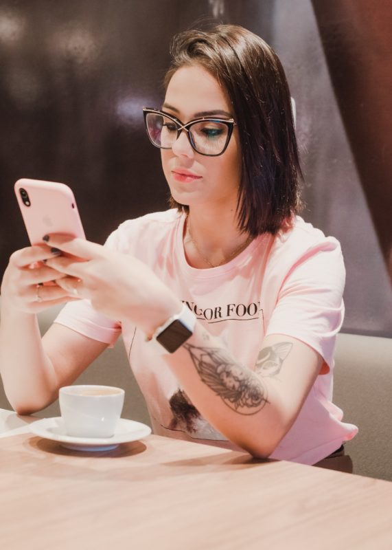 Девушка в кафе с телефоном пишет смс