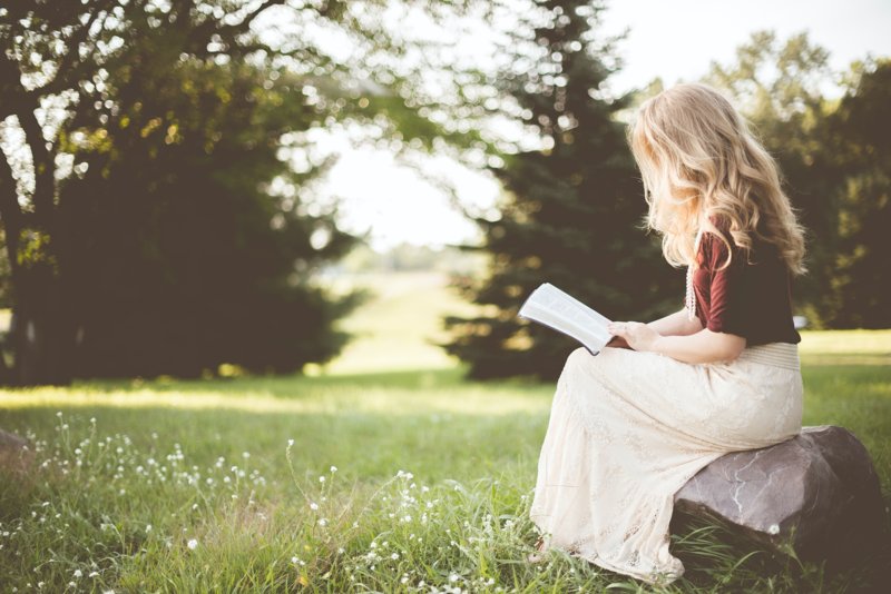 Девушка сидит с книгой в парке